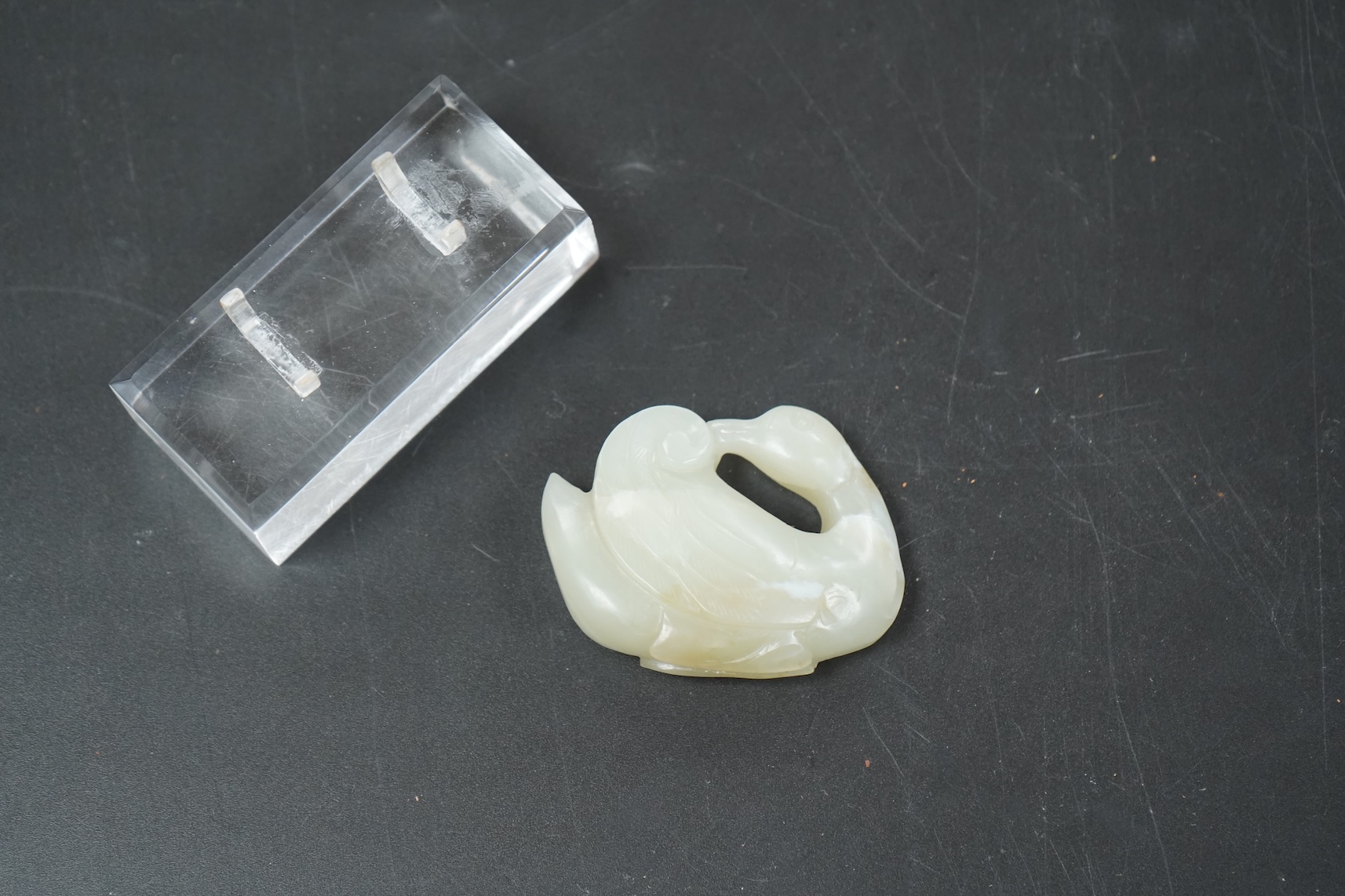 A Chinese celadon jade carving of a duck, Qing, with perspex stand, 5cm wide